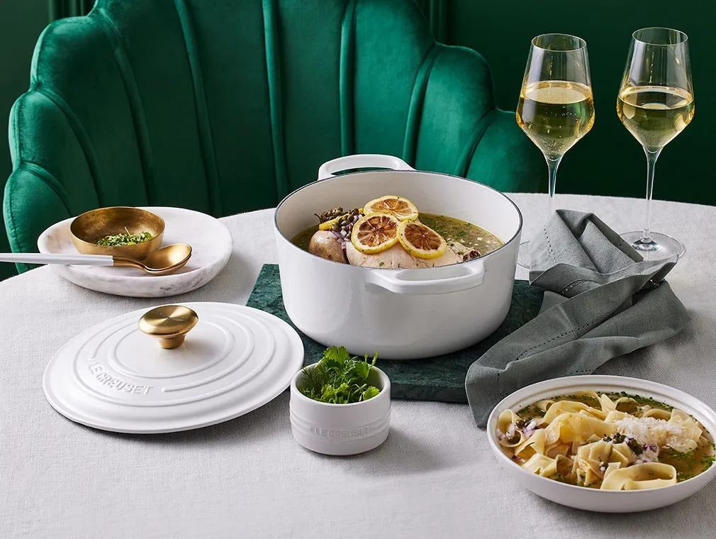 Whole poached chicken in a Le Creuset casserole, topped with lemon zest, capers and parsley