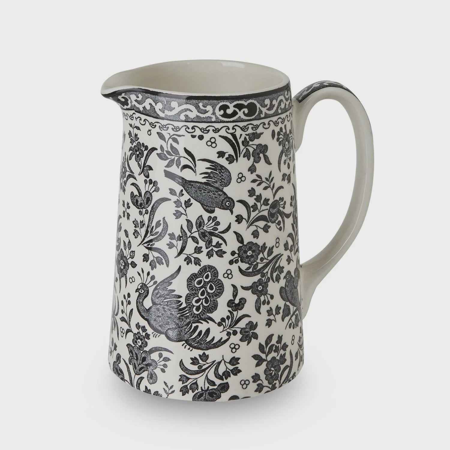 A ceramic pitcher with a black and gray floral and bird pattern on a white background