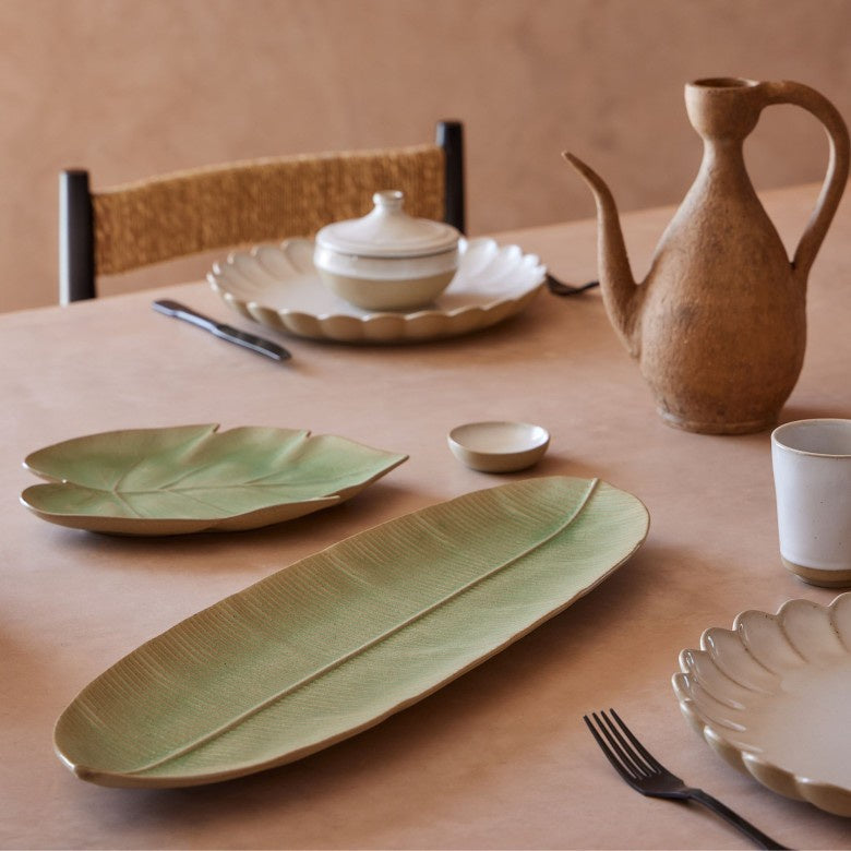 Dining table set with ceramic plates, a teapot, and cups on a wooden surface.
