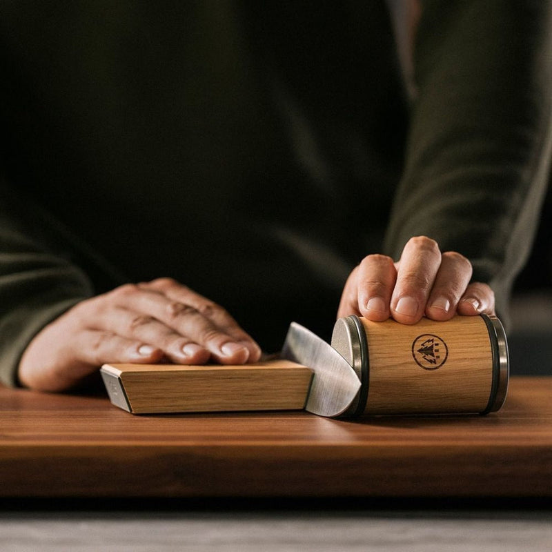 HORL 3 Oak knife sharpener being used with two hands rolling a knife across the whetstone