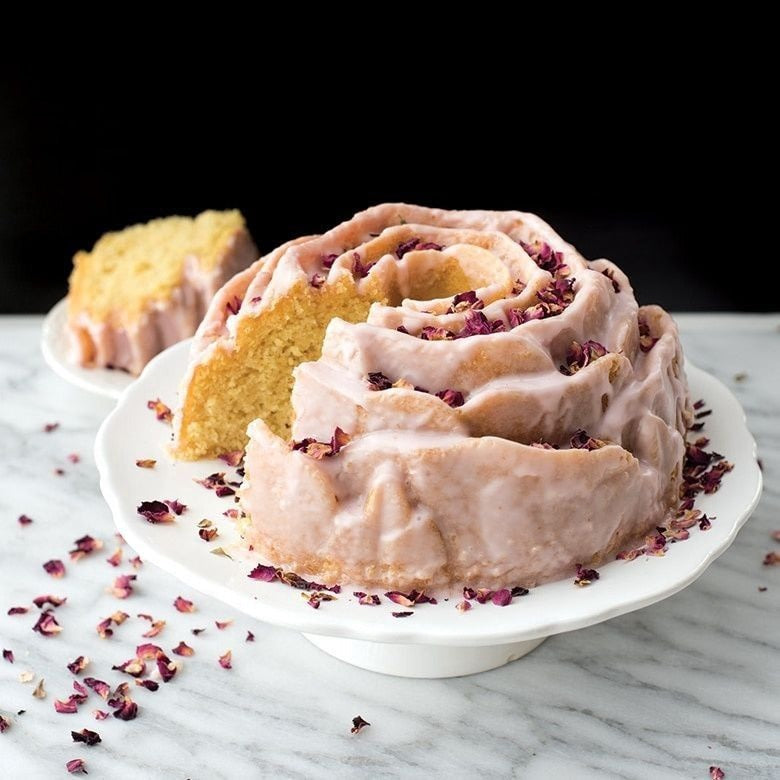 Nordic Ware Rose bundt cake with pink glaze and dried rose petals, sliced to show the detailed rose-shaped mould