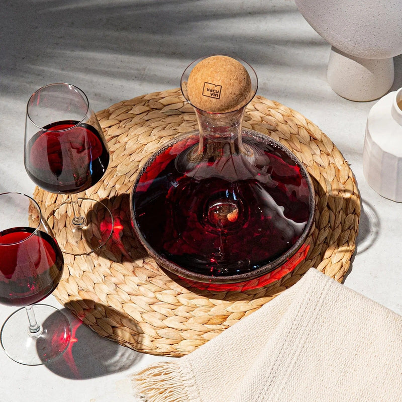Vacu Vin wine decanter filled with red wine, surrounded by glasses of red wine