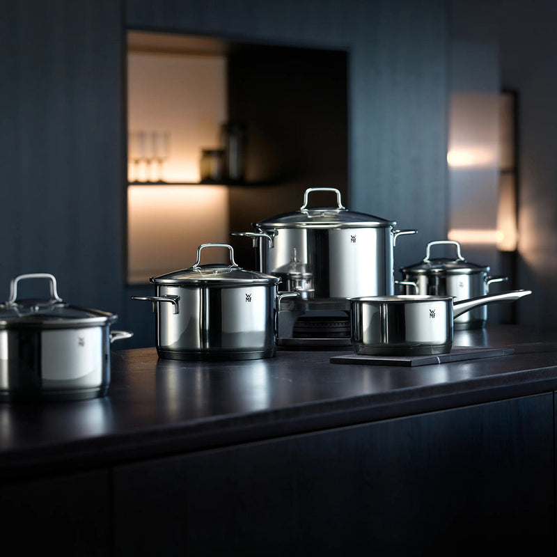 WMF Astoria 4 piece stainless steel cookware set with glass lids on a dark kitchen counter