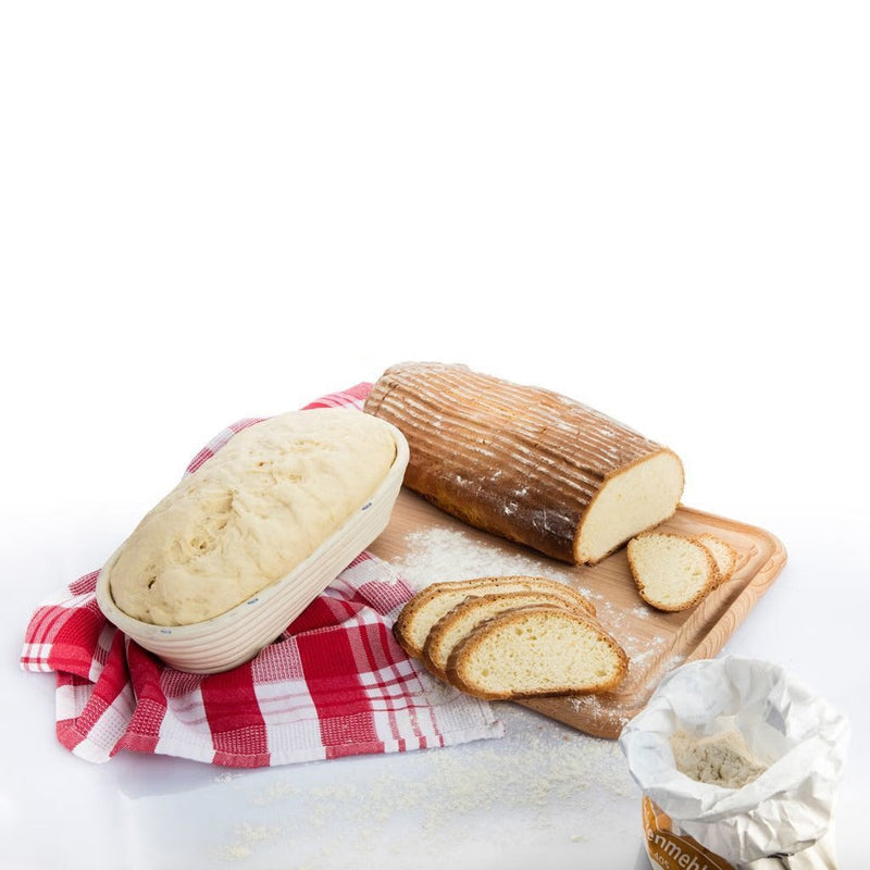 Westmark oval bread proving basket with rising sourdough next to a sliced baked loaf