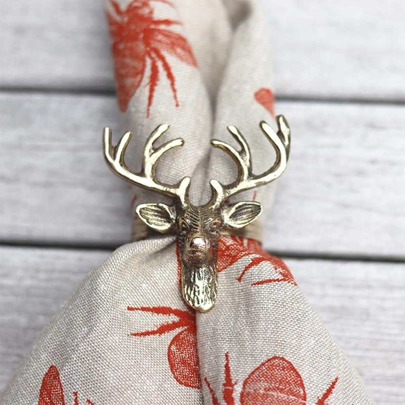Old Mill Road brass elk head napkin ring holding a linen napkin with a red print