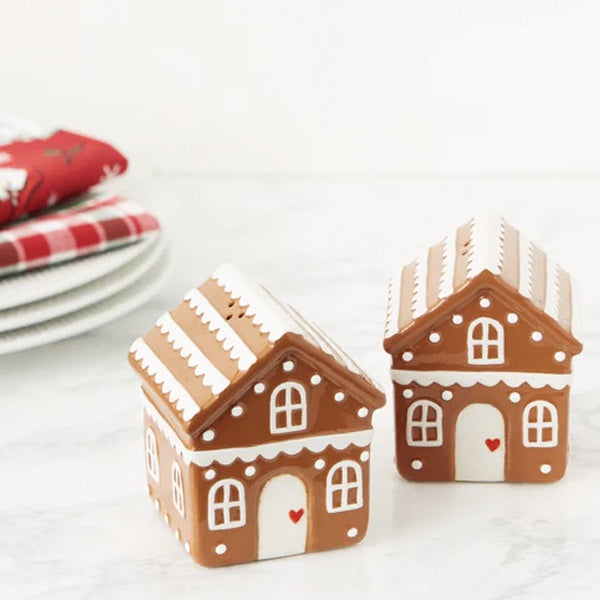 Gingerbread house salt and pepper set, two ceramic shakers with white icing detail, styled with plates and napkins