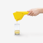 Dreamfarm Fluicer lemon squeezer in yellow, shown pouring juice into a glass