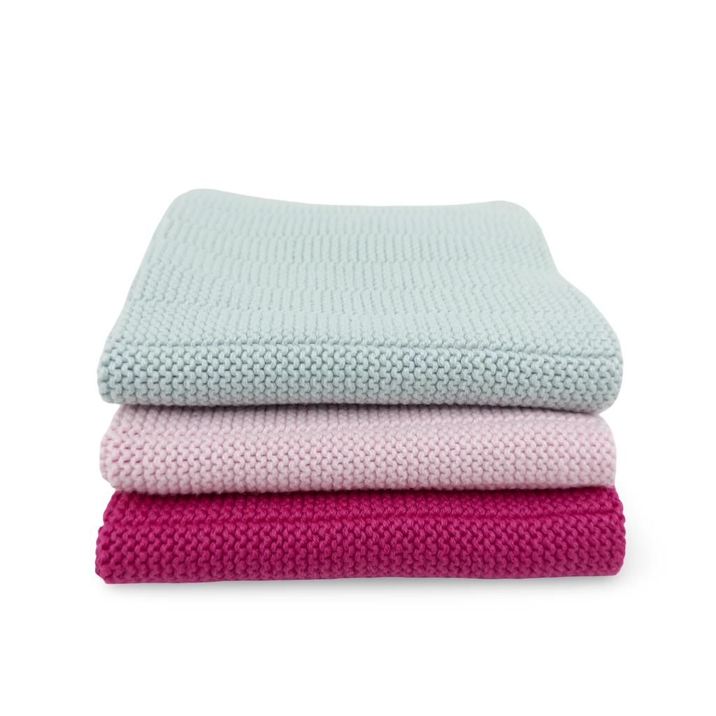 Stack of three folded blankets in light blue, pink, and magenta on a white background