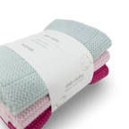 A three-pack of EcoVask hand-knit cotton dish cloths in light blue, pale pink, and magenta, wrapped in a white paper band.