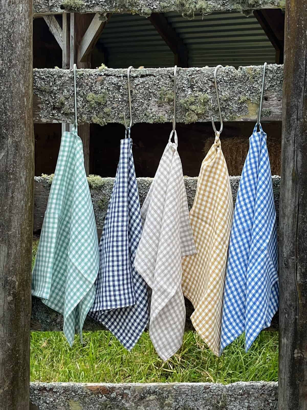 Ottoman Collection linen gingham tea towels in green, blue, grey, tan and navy, hanging on a rustic frame