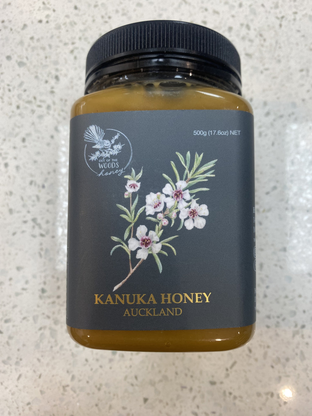Out of The Woods Kanuka Honey jar with a dark label and floral illustration