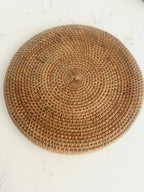 Barville natural rattan round placemat in brown, shown on a white marble surface