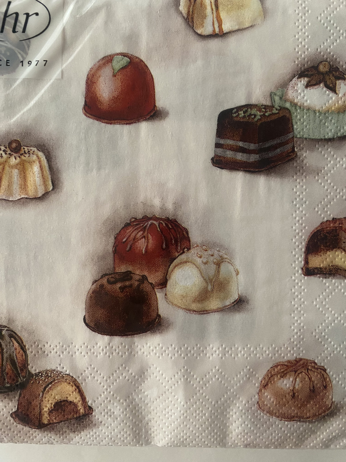 IHR Chocolates luncheon napkin with an illustrated pattern of chocolates and petit fours