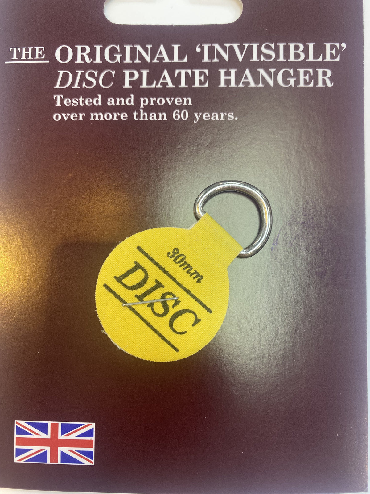 The Original Invisible Disc plate hanger, a 30mm yellow adhesive disc with a ring, on its card