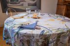 Telene Orchidea tablecloth with an orchid floral print, styled on a round table with place settings and wine glasses