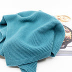 Ecovask hand towel in teal knit, shown folded with a magazine