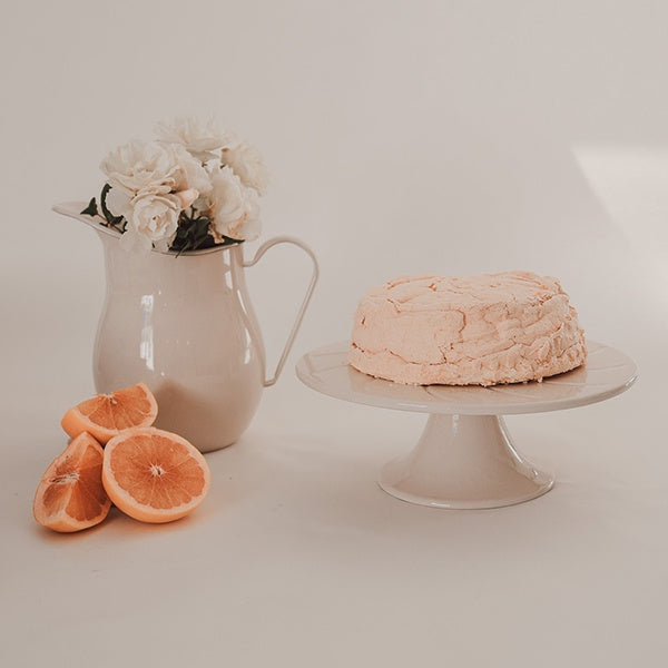 Dishy enamelware large cafe water jug, 2 litre, in almond cream, styled with flowers, a cake and grapefruit