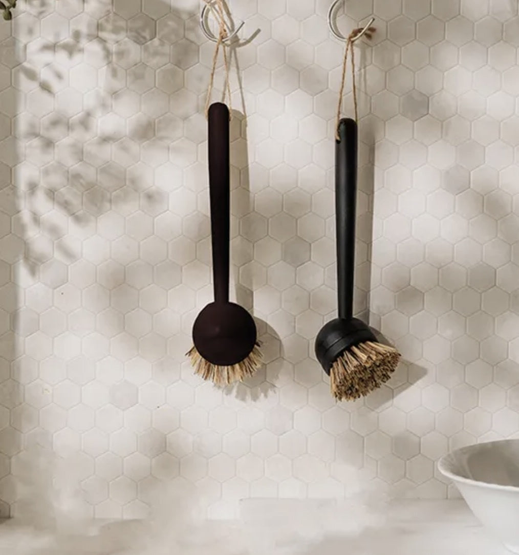 Simple Things screw-mount dish brush in black, shown hanging in a bathroom