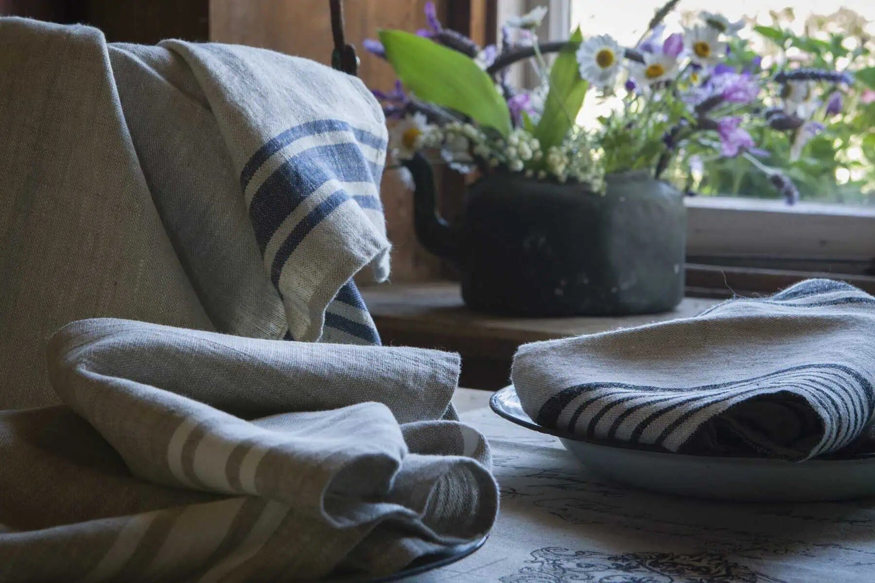 Ottoman Collection 100% linen tea towel in a Provence stripe, styled folded on a table with flowers