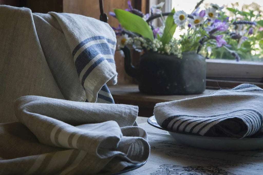 Ottoman Collection 100% linen tea towel in a Provence stripe, styled folded on a table with flowers