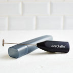 Aerolatte To Go milk frother, a small black handheld frother with its blue-grey case