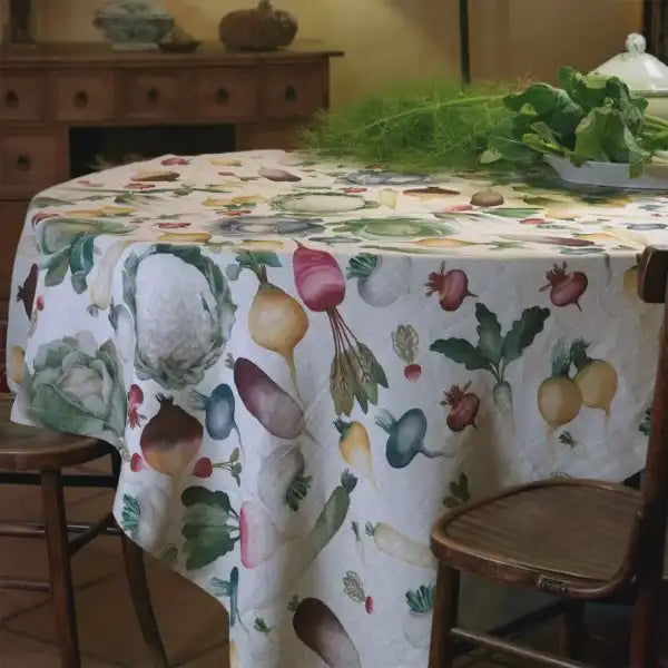 Tessitura Toscana Telerie Potager tablecloth with a print of colourful vegetables, styled on a round table