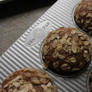 USA Pan Texas muffin pan with oat-topped muffins baking in the ridged aluminised steel cavities