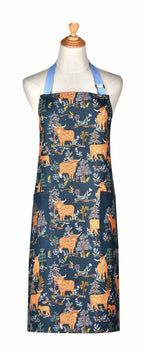 Ulster Weavers Connie the Cow cotton apron with Highland cows and trees on dark blue, shown on a mannequin