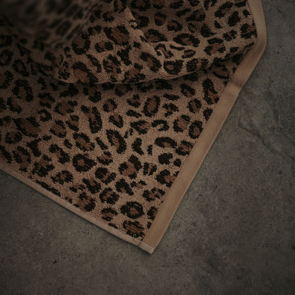 Baksana leopard print jacquard finger towel in brown and black, folded on a dark surface