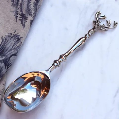 Old Mill Road elk serving spoon in silver with an antler handle, shown on marble with a linen cloth