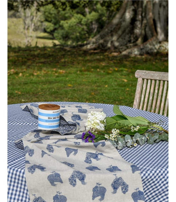 Raine & Humble Henrietta table runner with blue hen prints on natural linen, set on a gingham table outdoors
