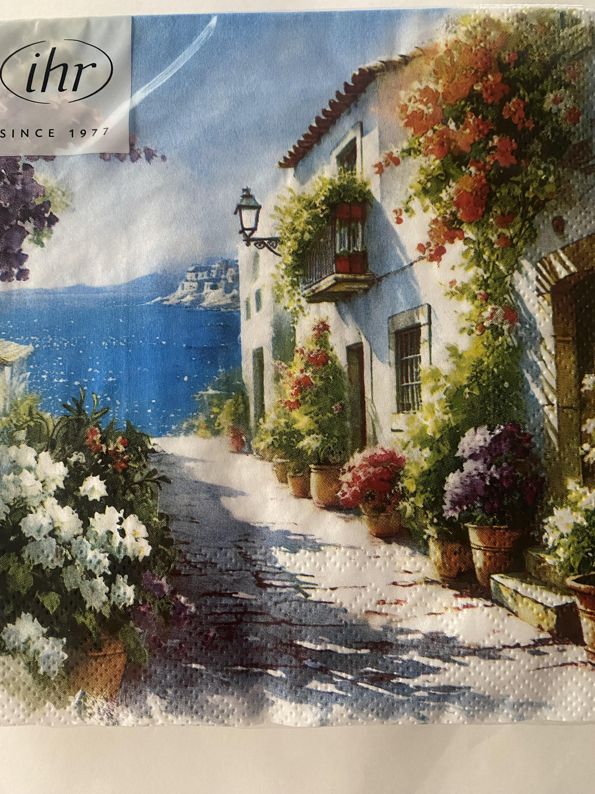 IHR luncheon napkin with a painted Mediterranean street scene of flower-filled balconies and the sea